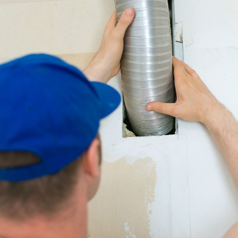 Man setting up ventilation system indoors.