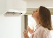 Women dying from the heat standing in front of the air conditioner.