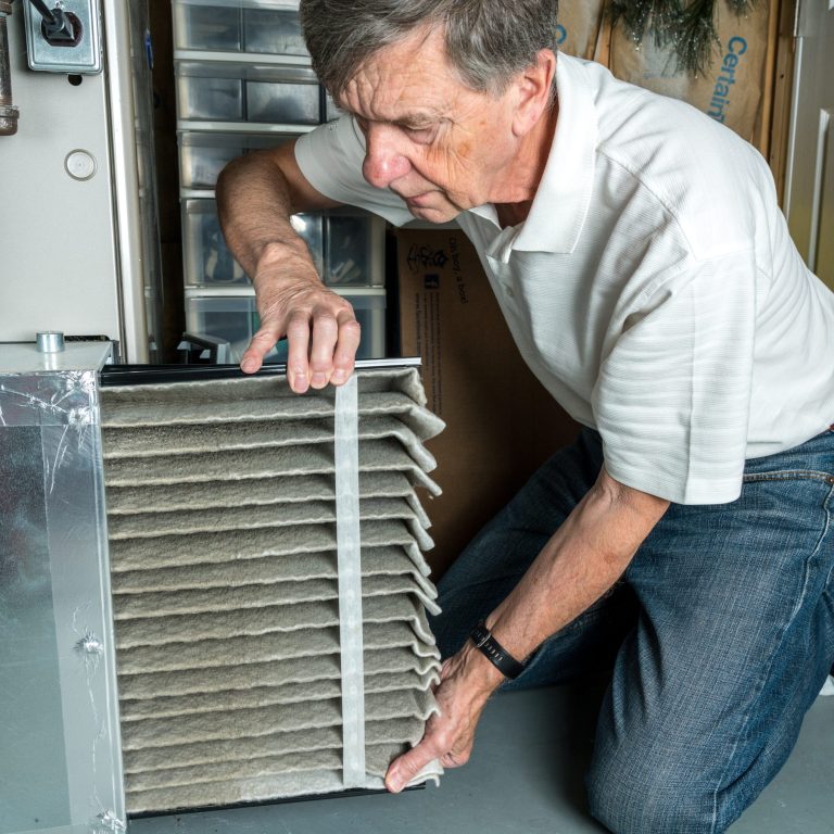 Senior man changing a dirty air filter in a HVAC Furnace hvac furnace