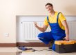 Young repairman contractor repairing heating panel