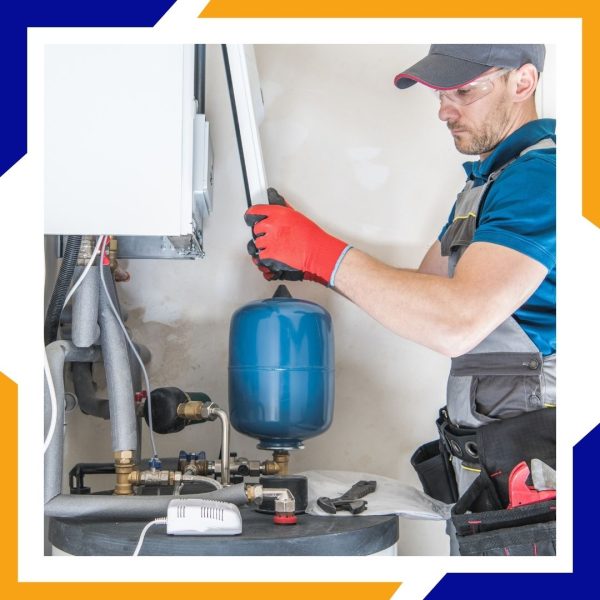 Heating Installation Greeley 4 A technician in safety glasses and gloves works on the piping of a water heater and expansion tank.