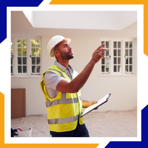 Heating Installation Loveland 1 A male contractor in a hard hat and safety vest inspects a room for an HVAC installation.