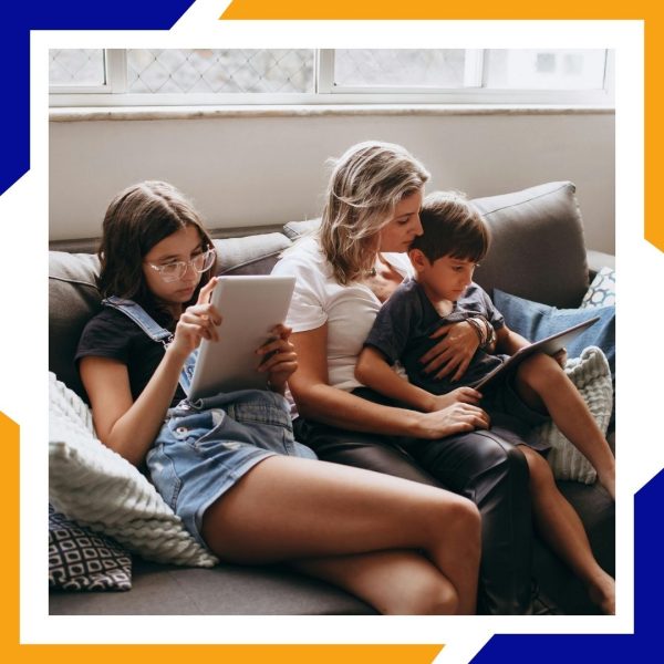 Heating Repair Brighton 4 A mother sits on the couch with her two children, all relaxed and using tablets in a warm home.