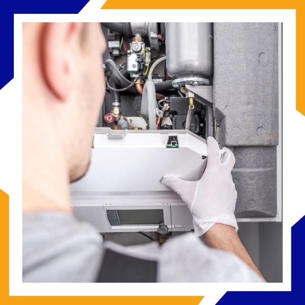A technician wearing white gloves carefully replaces the front panel of a furnace.