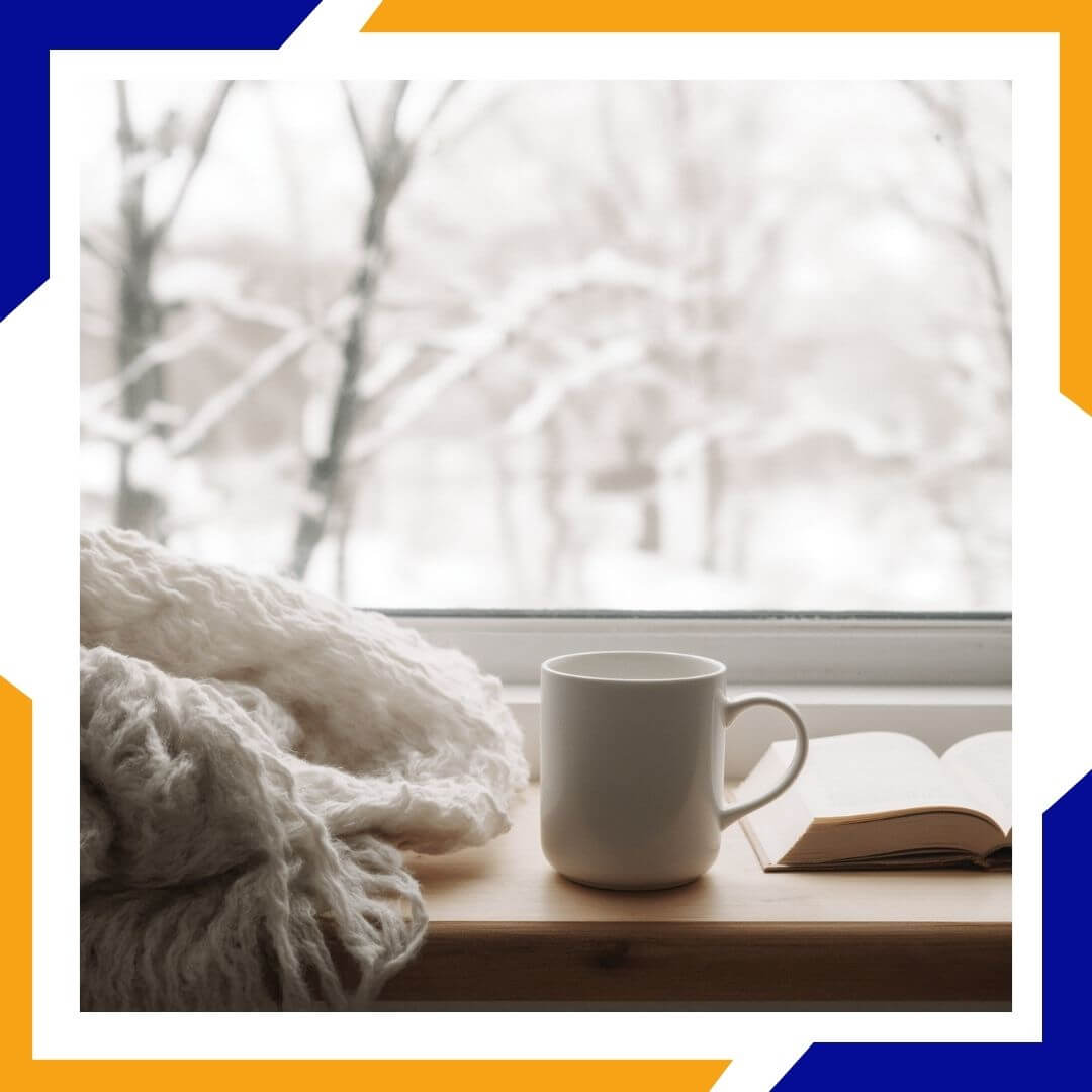 mug and blanket near snowy window